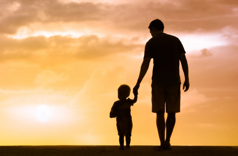 Père marchant avec un enfant vers un coucher de soleil. Représentation de l'éducation d'un enfant autiste