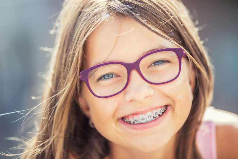 Jeune fille souriante portant un appareil dentaire et des lunettes. Jeune fille blonde caucasienne portant un appareil dentaire et des lunettes.